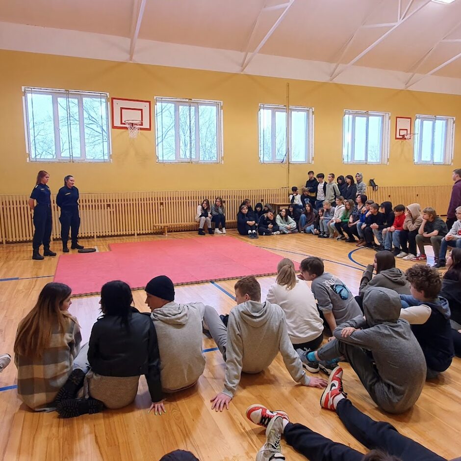 Sporta zāle, skolēni sēž uz grīdas