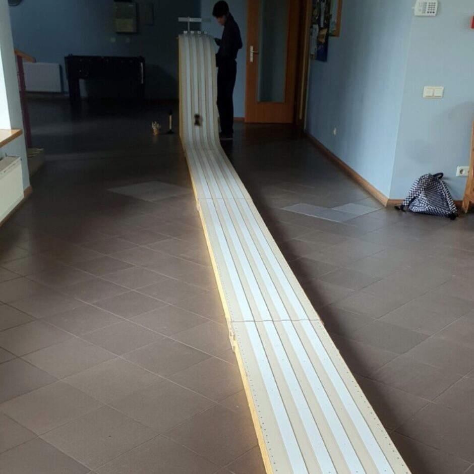 Gara, daudzjoslu sacīkšu trase rotaļu automašīnām stiepjas pa telpas flīzēto grīdu. Pie trases paaugstinātā starta punkta stāv zēns tumšās drēbēs, blakus redzama maza mašīnīte. Fonā redzamas gaiši zilas sienas un galda futbols.