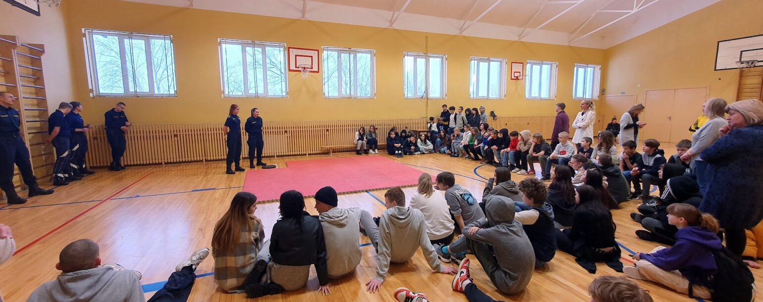 Sporta zāle, skolēni sēž uz grīdas